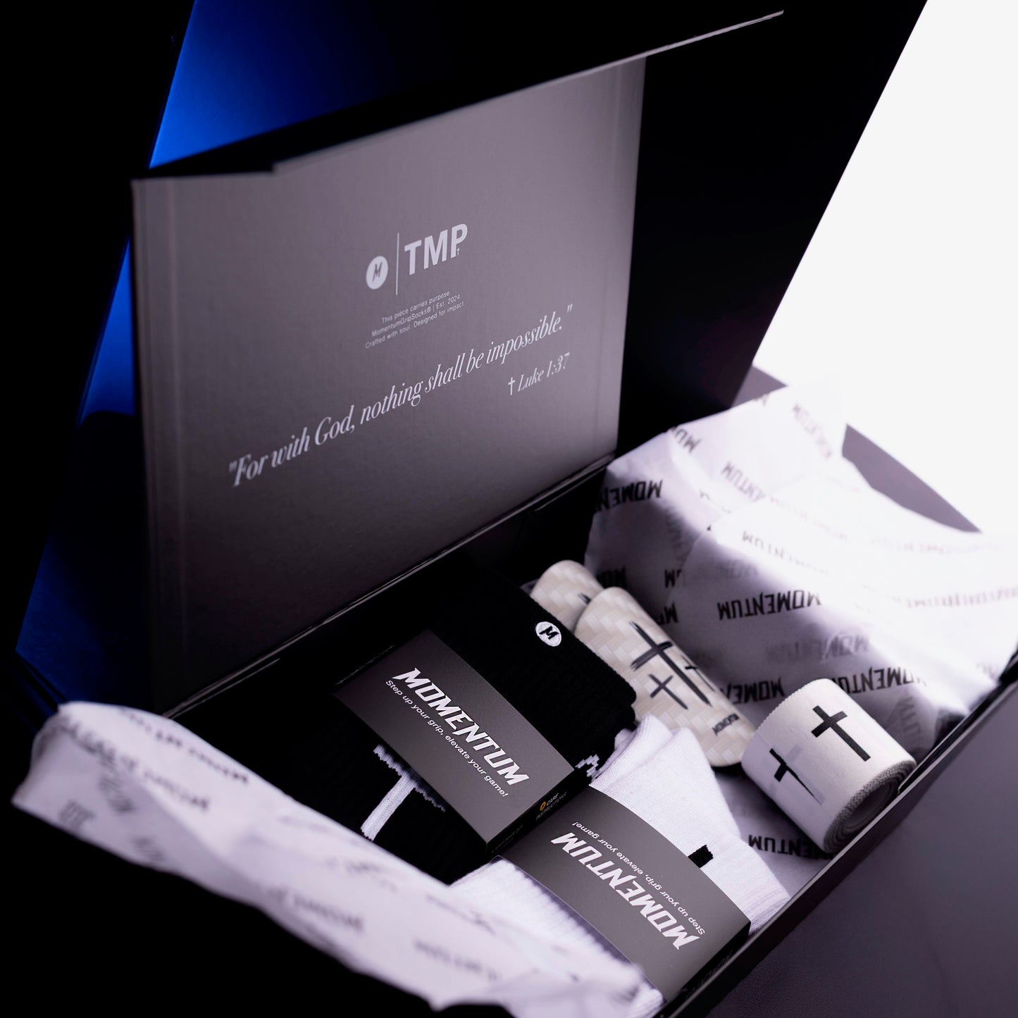 Box of socks with 'Momentun' branding and a black box inside, featuring the text 'For with God, nothing shall be impossible.'