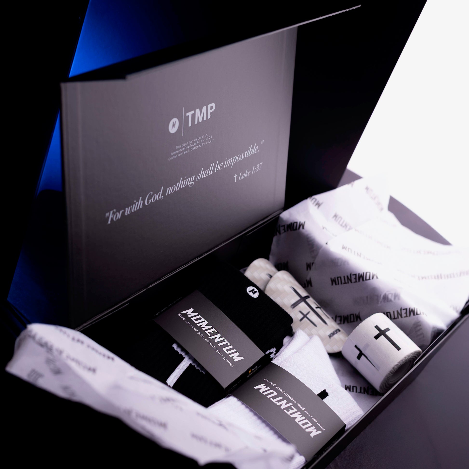 Box of socks with 'Momentun' branding and a black box inside, featuring the text 'For with God, nothing shall be impossible.'